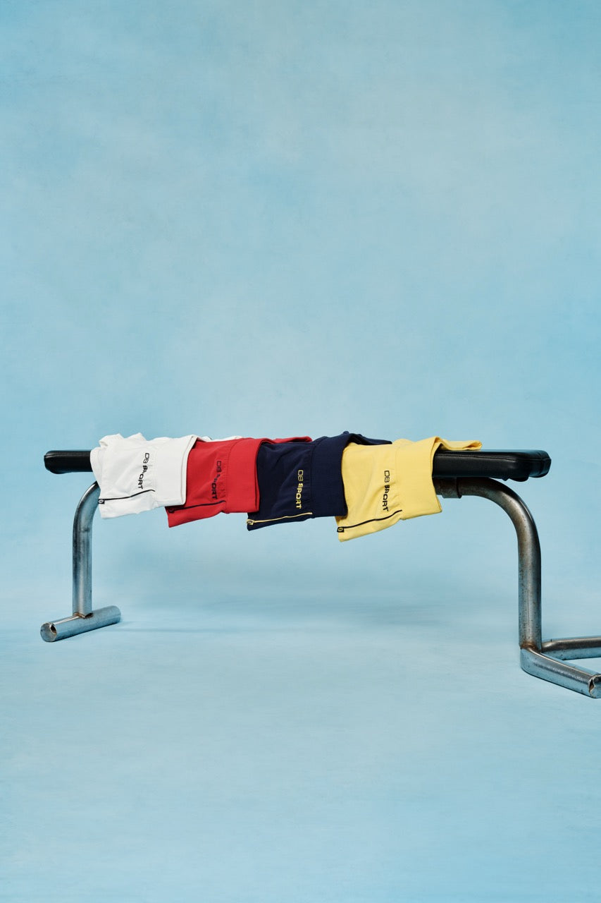 Four pairs of shorts hanging on a metal bar against a blue background