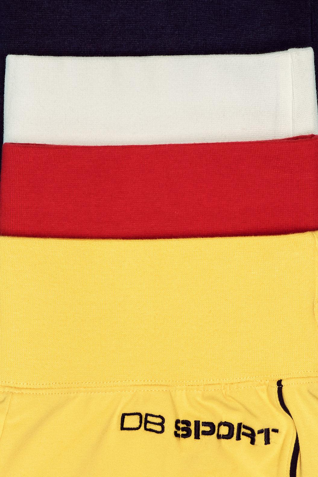 Close-up of a sport shorts with red, white, and yellow sections, featuring 'DB Sport' branding.