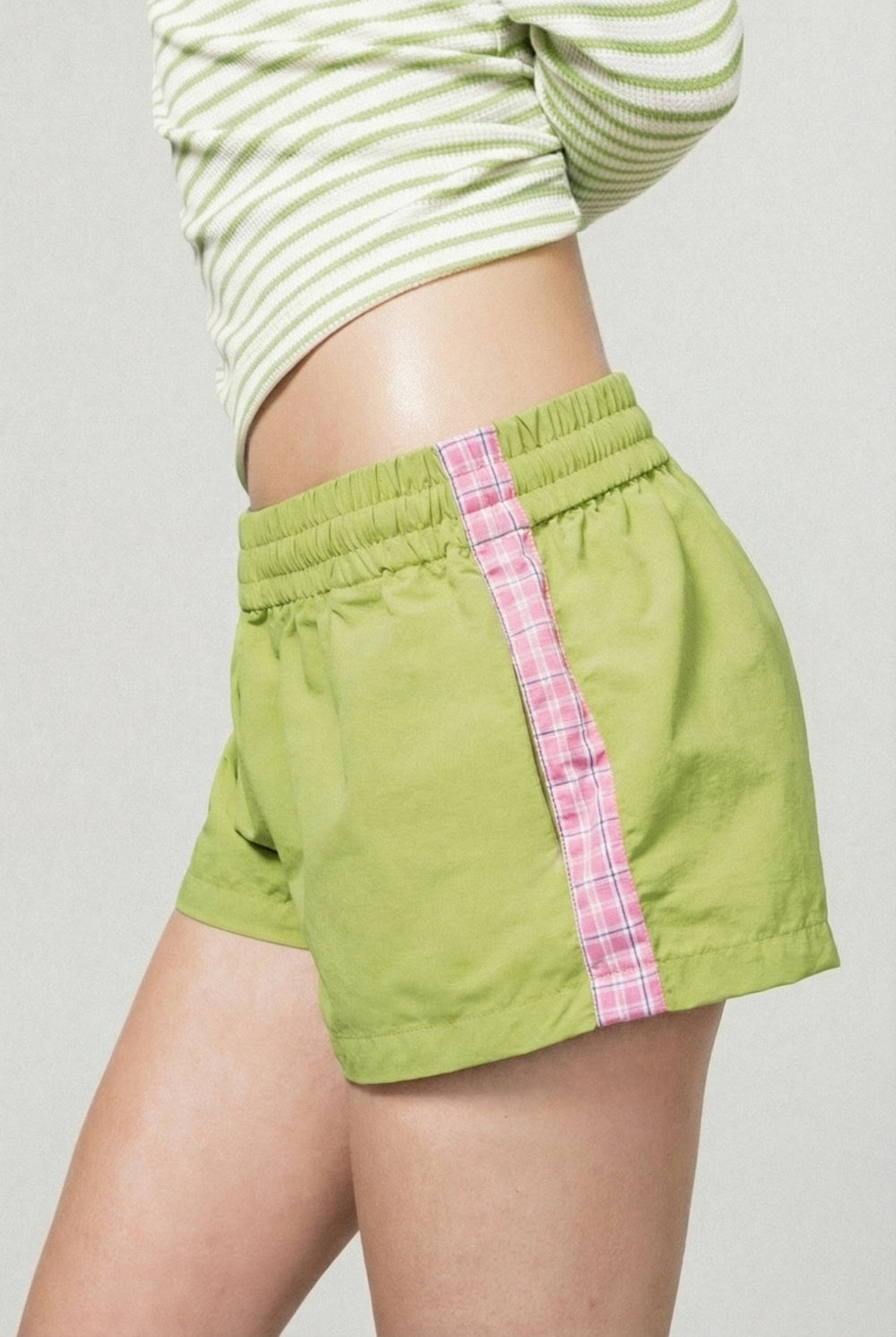 Green shorts with pink plaid accents worn by a person on a plain background |m1