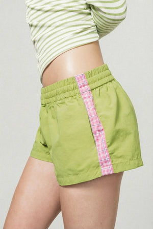 Green shorts with pink plaid accents worn by a person on a plain background |m1