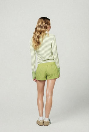 Woman wearing a green striped sweater and shorts on a white background |m1