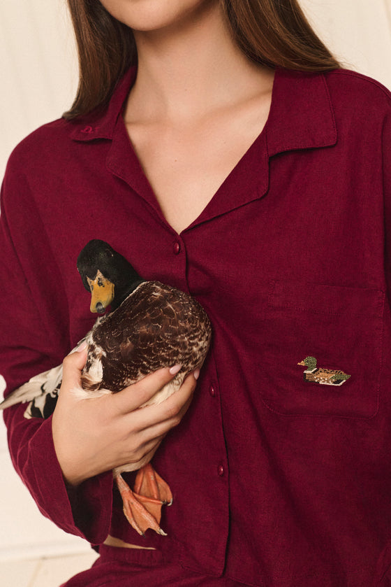 Person wearing a burgundy pajama shirt with a duck design, holding a duck. |M1