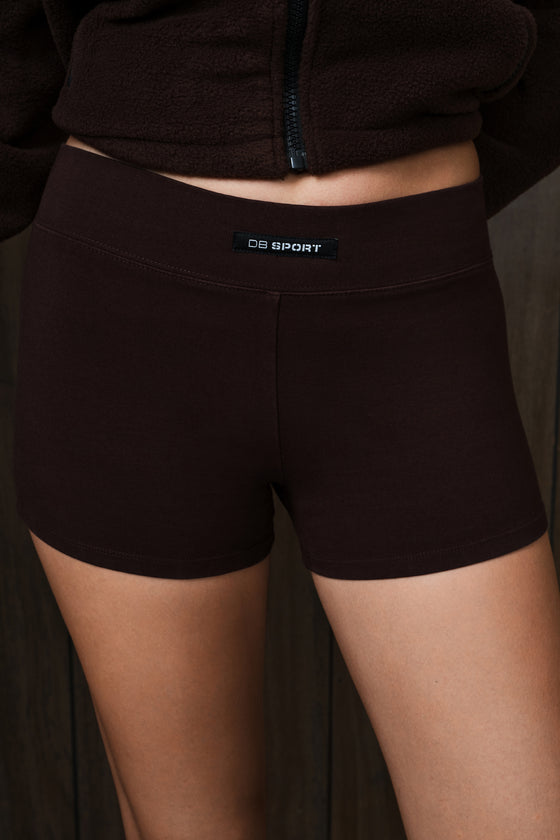 Close-up of a person wearing dark brown athletic shorts with a visible waistband label reading 'DB SPORT'.
|M1