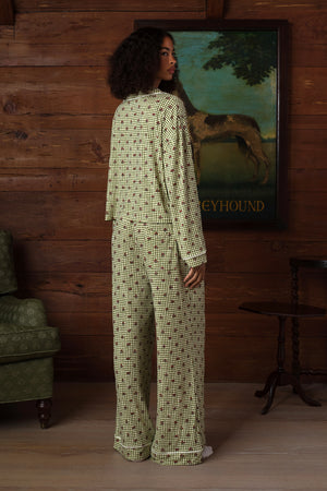 Back view on a model of a long-sleeve pajama set in green and cream gingham with a small red floral print, white piping and wide-leg pants. |M1