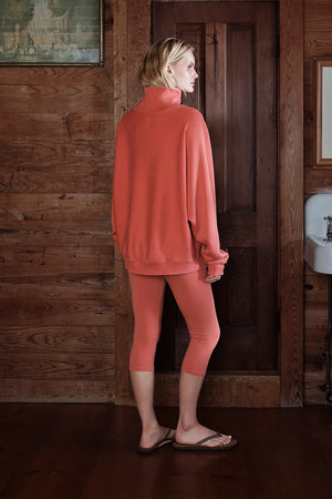 Person wearing a pink outfit standing in a rustic wooden interior.
|M1