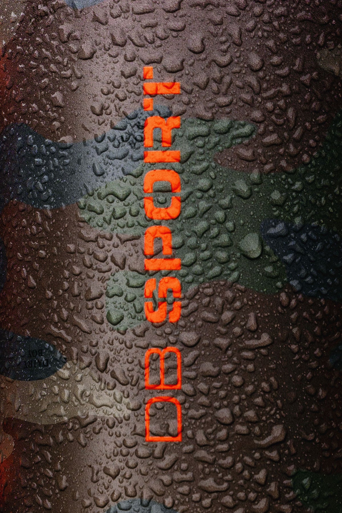 A close-up of a cylindrical product covered in water droplets, featuring a dark camouflage pattern and vertical orange text reading 'DB SPORT'.