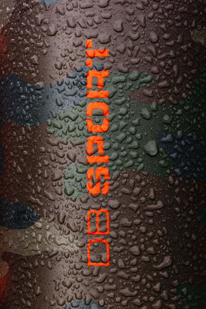 A close-up of a cylindrical product covered in water droplets, featuring a dark camouflage pattern and vertical orange text reading 'DB SPORT'.