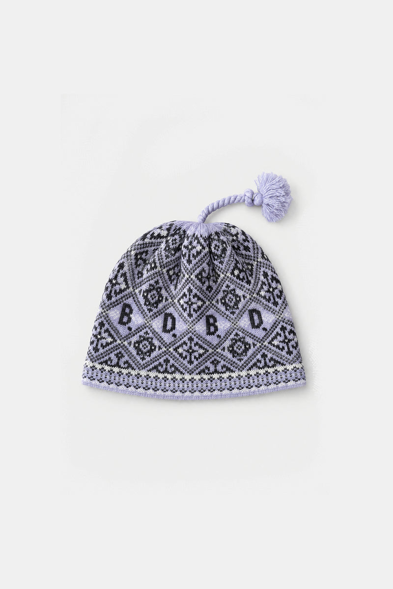A lavender knit pom-pom beanie hat featuring a black and white geometric pattern with the letters 'D B D B' repeated, finished with a light purple pom-pom and trim, shown on a plain light gray background.