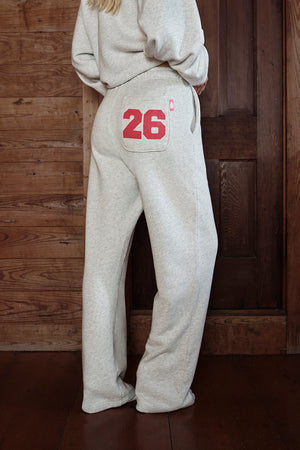 Person wearing a beige hoodie and pants with the number 26 on a wooden background
|M1