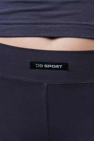 Close-up of a person wearing dark grey athletic mini shorts with a black waistband label reading 'DB SPORT'.