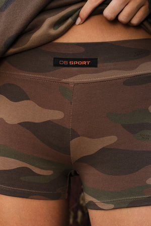 Close-up of a person wearing camouflage athletic shorts with a visible waistband label reading DB SPORT.
