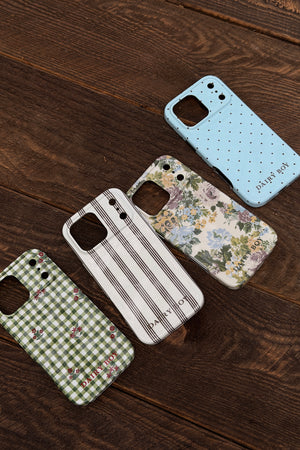 Light blue phone case with small dark polka dots and DAIRY BOY lettering, shown back-side up beside three other patterned cases.