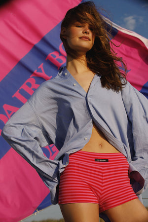 Woman wearing a light blue shirt and red striped shorts with a colorful background