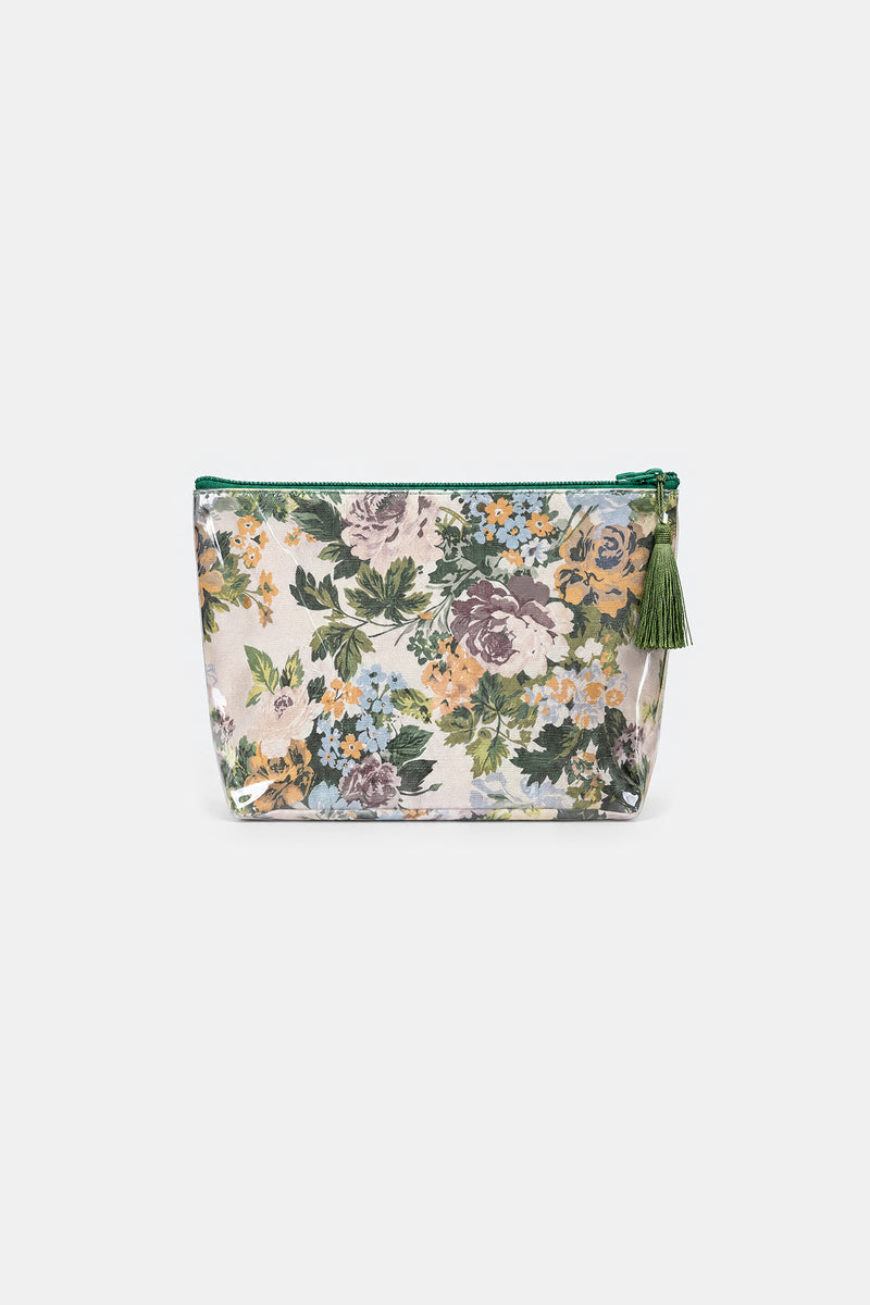 Front view of a clear-fronted makeup bag over a floral print in purple, yellow, blue and green, with a green zip and tassel.