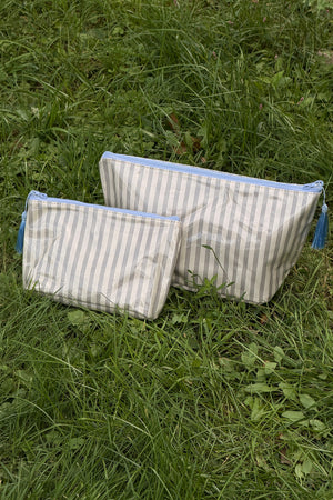 Two zip-top makeup bags in cream with thin brown stripes, light blue zips and blue tassel pulls, shown side by side.