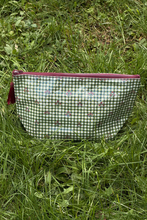 Green and white gingham makeup bag with small red floral motifs, a burgundy zip and a burgundy tassel, shown front on.