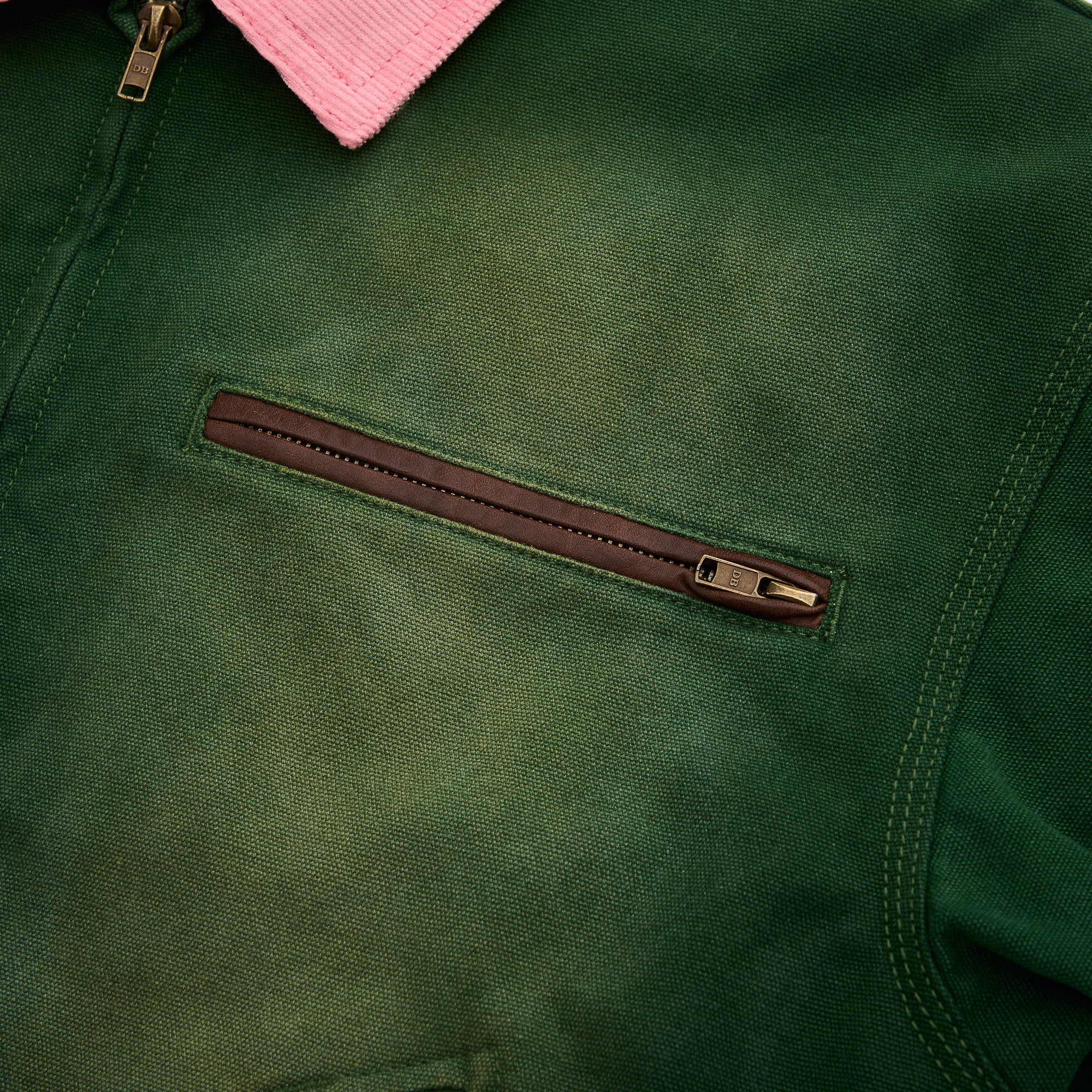 Close-up of a green jacket with a brown zipper pocket