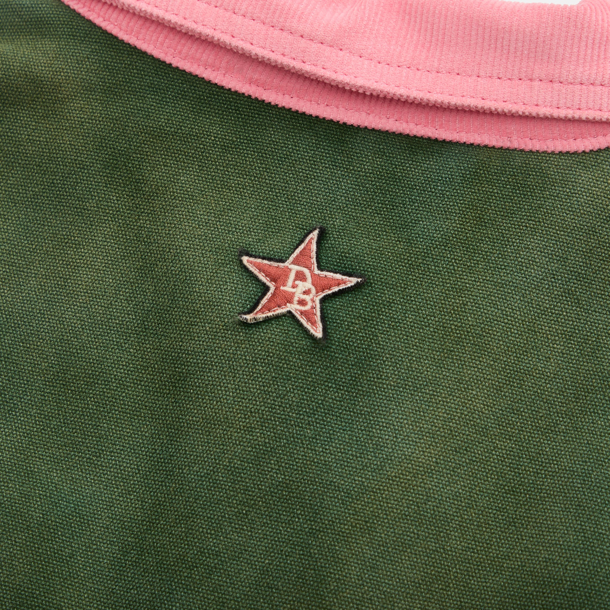 Green jacket backside with a star-shaped logo on a pink collar