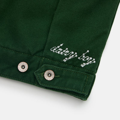 Close-up of a green garment with 'dating boy' embroidery on a white background