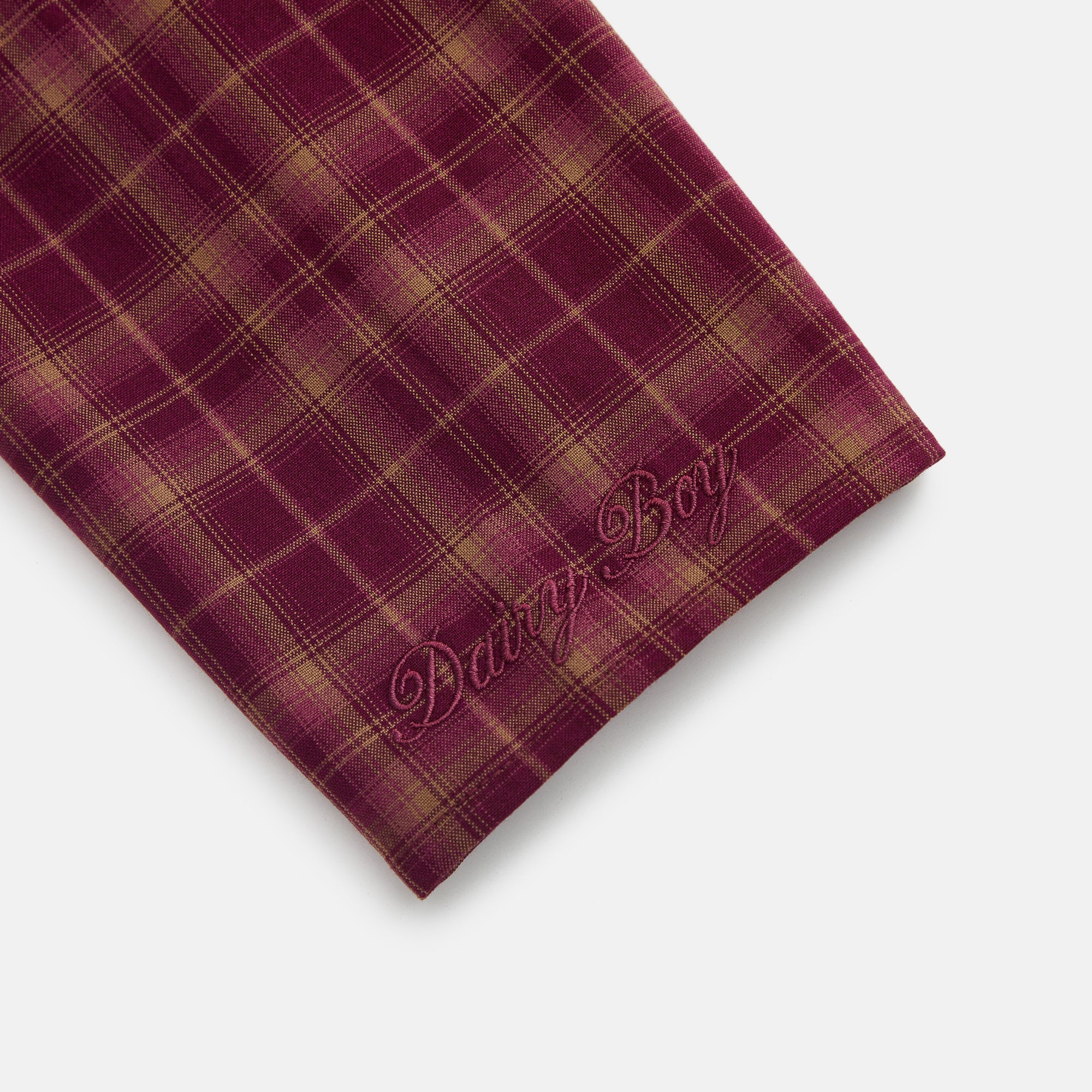 Plaid fabric with 'Dairy Boy' embroidery on a light gray background