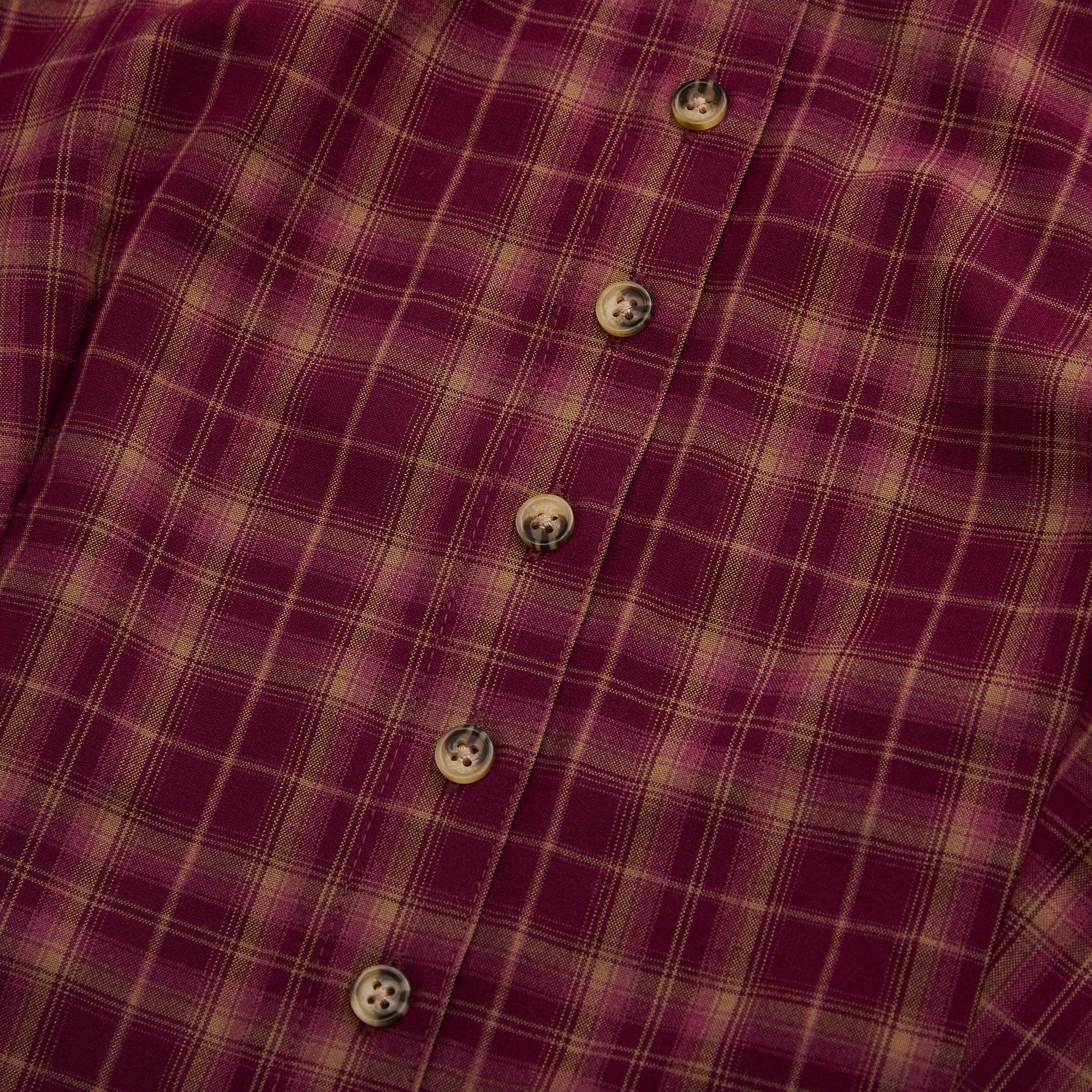 Close-up of a red and beige plaid dress front with buttons