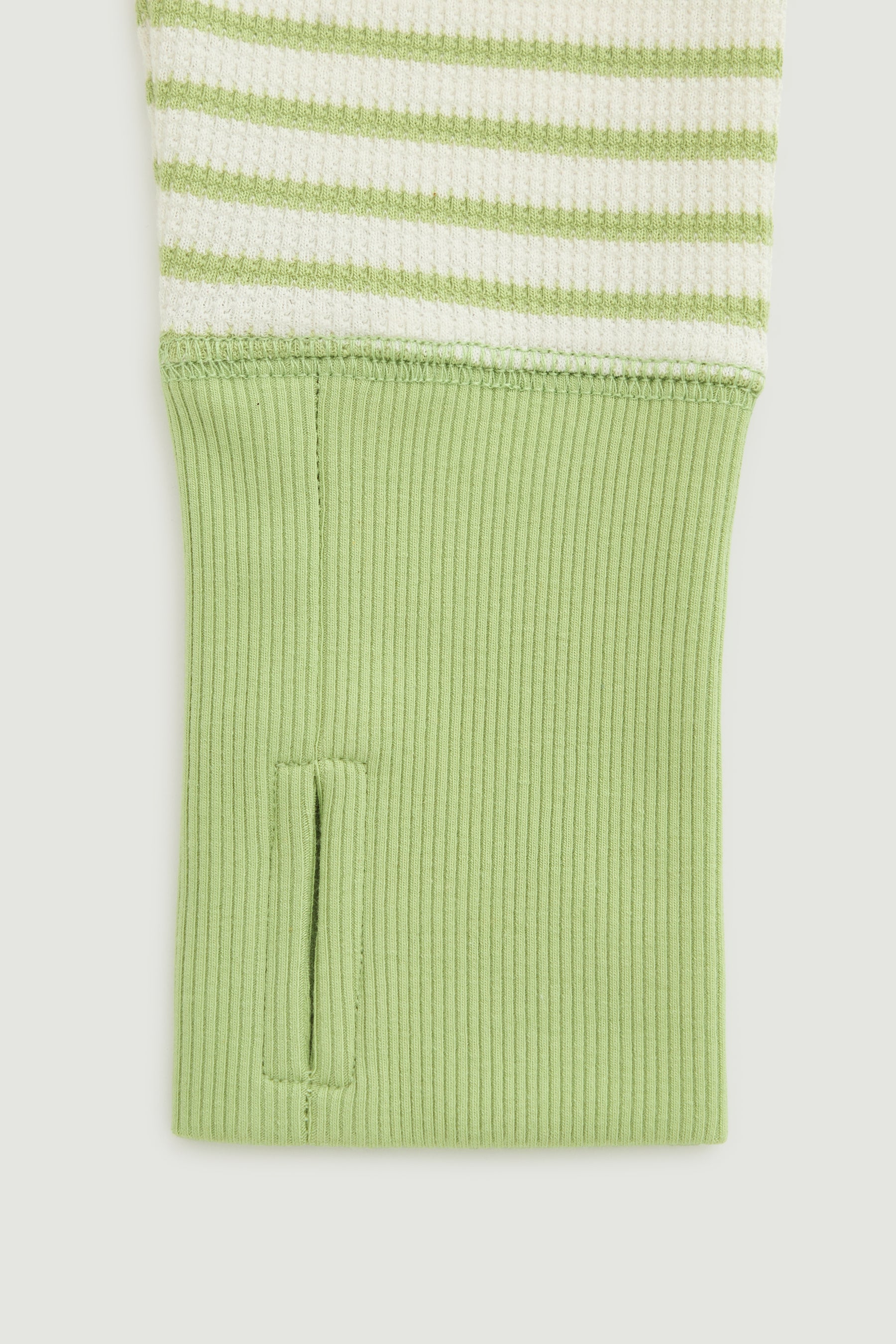 Green and white striped shirt with green cuff on a light gray background