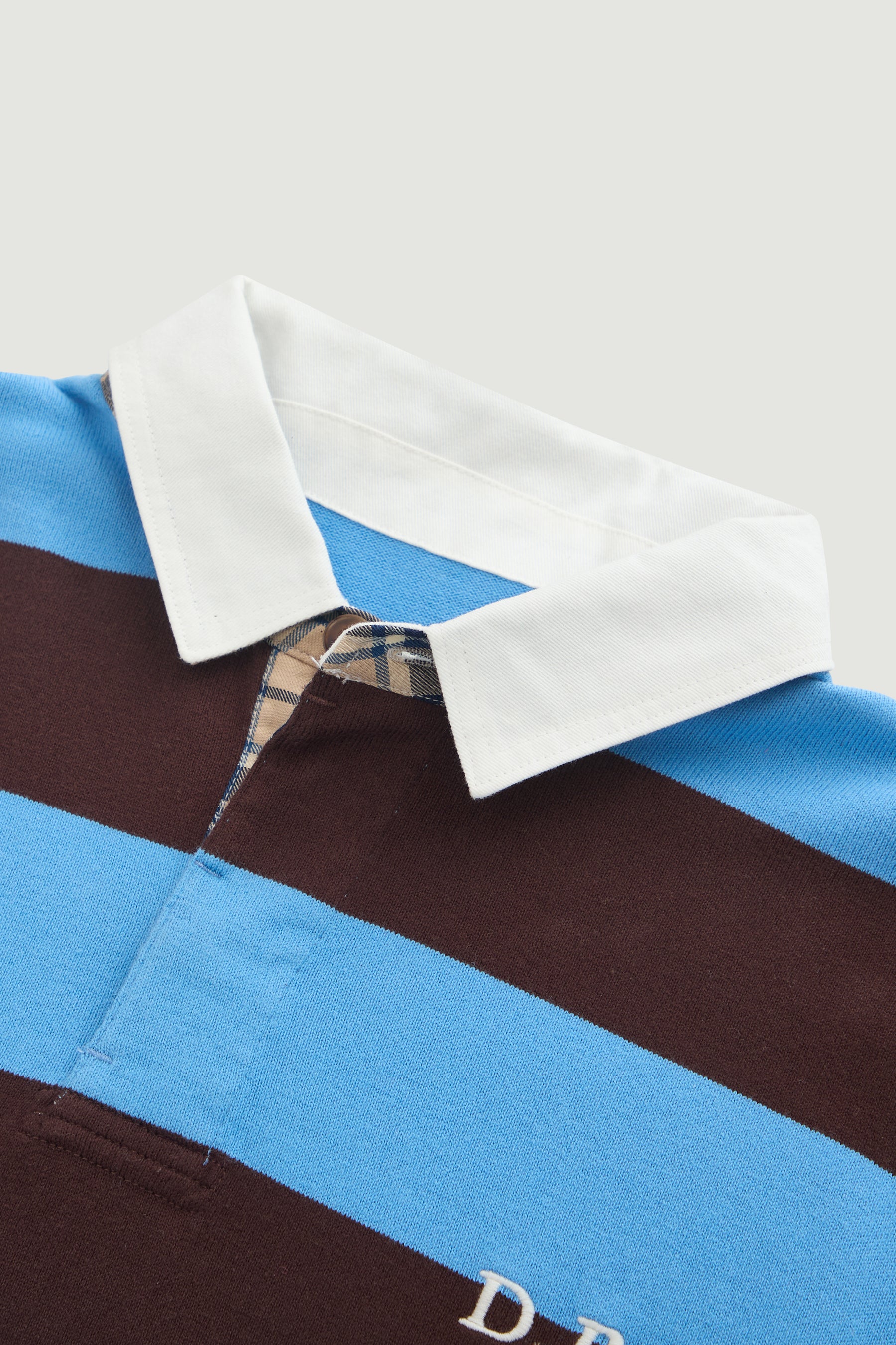 Close-up of a shirt with a checkered pattern and blue and brown stripes on a white background