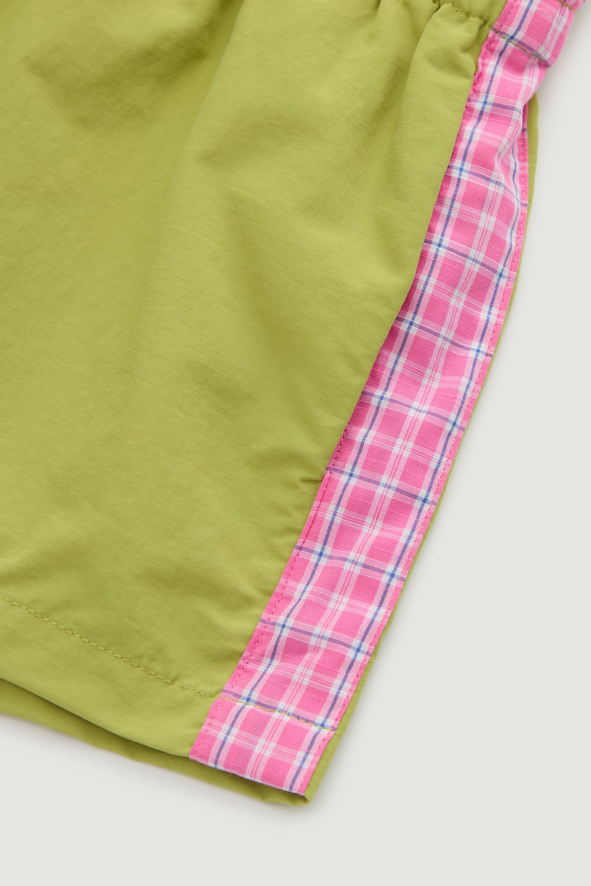 Green shorts with pink plaid trim on a white background