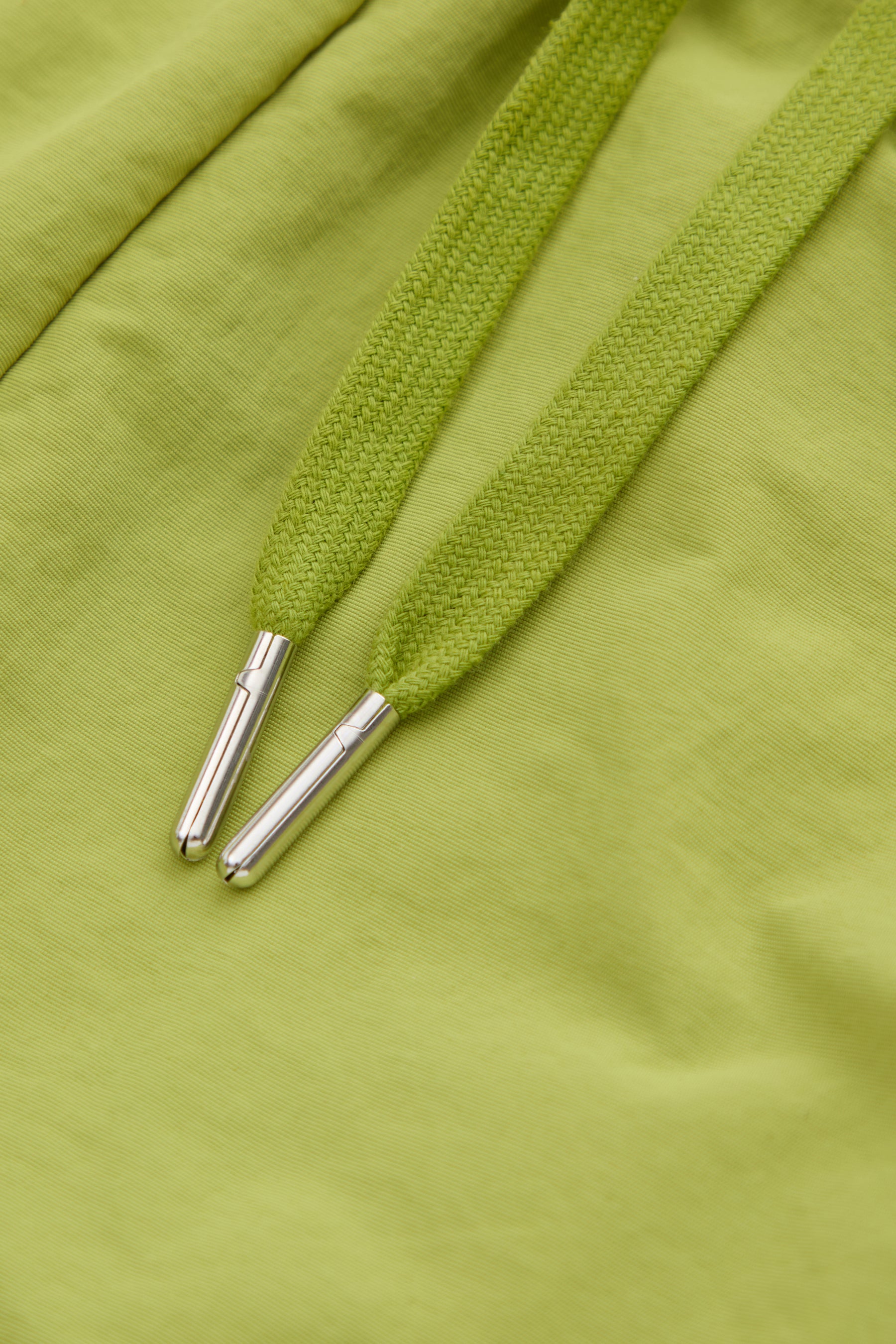 Close-up of green  drawstring with metal eyelets on a green fabric shorts