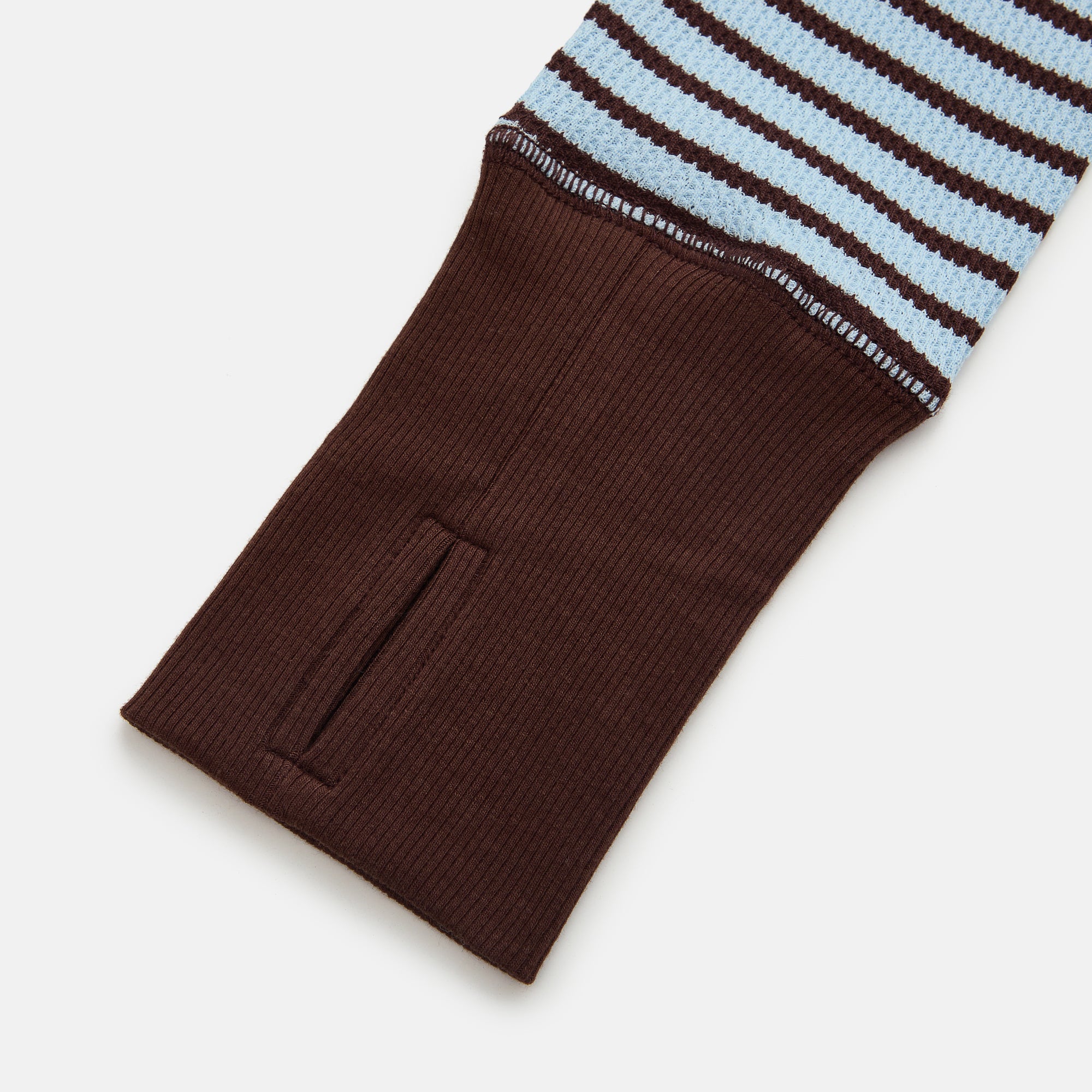 Brown sock with blue and white striped top on a light gray background
