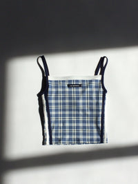 Plaid-patterned tank top with black trim on a white background