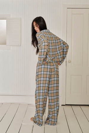 Person wearing a plaid outfit standing in a room with white walls and wooden floor. |M1