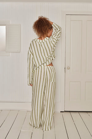 Person wearing a green and white striped pajama set in a minimalistic room. |M1