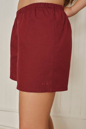 Maroon shorts with initials 'D.B.' on a neutral background. |M2