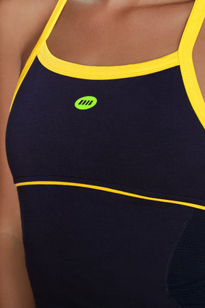 Close-up of a dark navy athletic tank top with bright yellow trim and a small green logo on the chest, worn by a model.
|M1