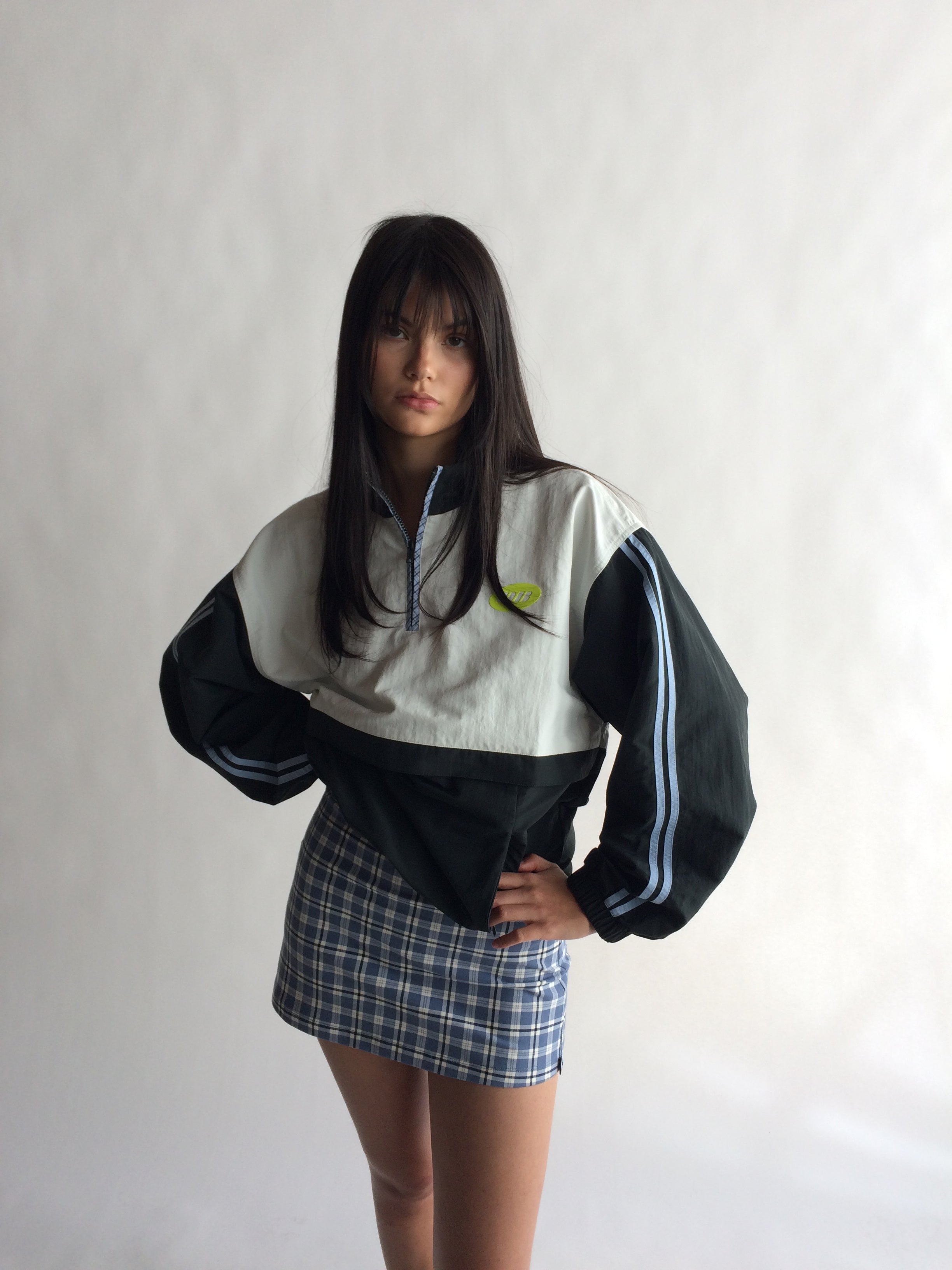 Person wearing a black and white jacket with a plaid skirt on a plain background |M2