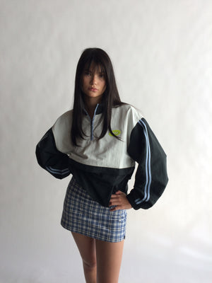 Person wearing a black and white jacket with a plaid skirt on a plain background |M2