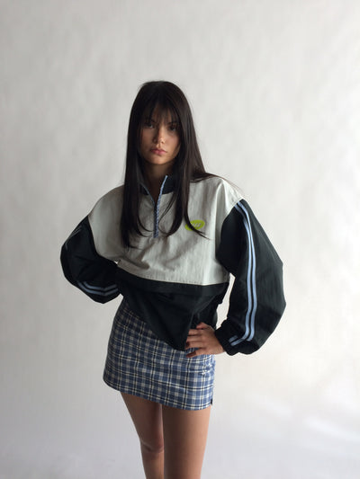 Person wearing a black and white jacket with a plaid skirt on a plain background |M2