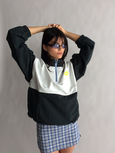 Person wearing a black and white jacket with a plaid skirt against a plain background |M2