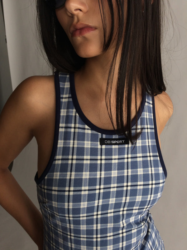 Woman wearing a blue plaid dress with a brand label on a neutral background |M2