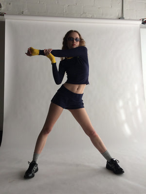 Person posing in a studio setting with a white backdrop  |M1