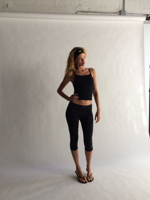 Woman wearing a black athletic outfit standing against a white background  |M1