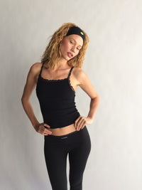Woman wearing a black tank top and leggings against a plain background  |M1