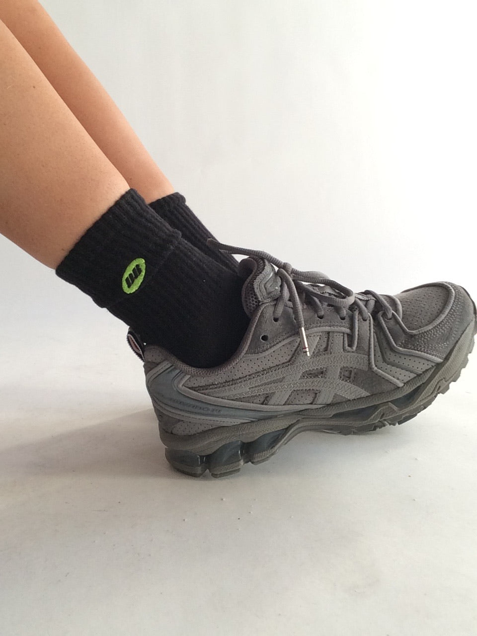 Gray athletic shoe with black sock on a white background