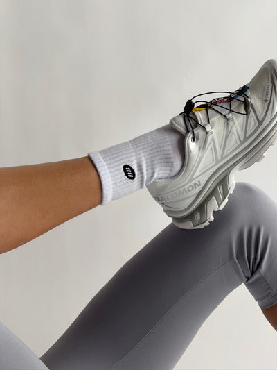 Person wearing a gray sock and shoe with a neutral background
