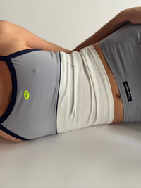 Person wearing a gray tank top and white shorts on a plain background |M1