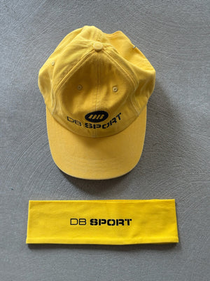 Yellow cap and headband with 'DB Sport' logo on a gray background