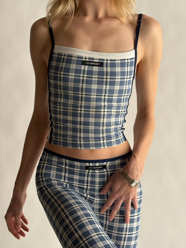 Person wearing a blue plaid top and capris with a visible brand label on a neutral background  |M1