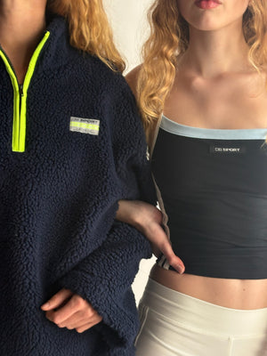 Two people wearing navy fleece and black sports bra with visible brand logos.  |M1