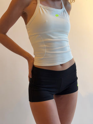 Person wearing a white athletic tank top and black shorts on a plain background |M1
